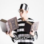 六法全書を片手に勉強する囚人